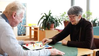 Kaksi henkilöä pelaa peliä pöydän ääressä