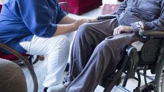 Hoitaja pitää iäkästä miestä kädestä.