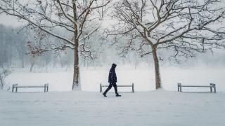 Henkilö kävelee lumisessa maisemassa