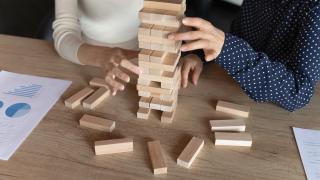 kaksi ihmistä rakentaa jenga-tornia