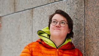 Oliver oranssissa toppatakissa ulkona. Katsoo kameraa