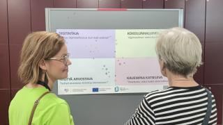 VAKEn työntekijä ja vanhempi nainen katsovat taulua yhdessä.