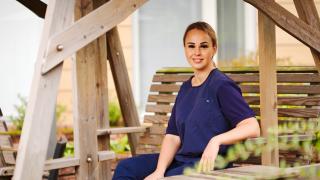 Grete Paap istuu keinussa hoivakodin pihalla.