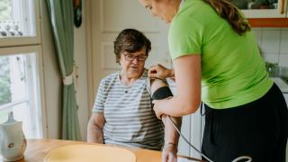 Kotihoidon hoitaja mittaa asiakkaalta verenpaineen.