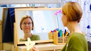 Puheterapeutti Merja Hartikka katsoo itseään peilistä.