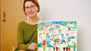 Puheterapeutti Merja Hartikka pitää kädessään värikästä kuvataulua.