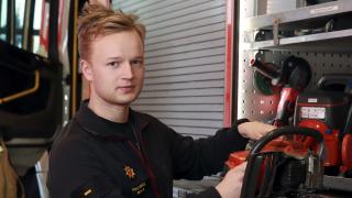 Palomies Miika Kilpeläinen seisoo Pelastuslaitoksella moottorisaha kädessään.