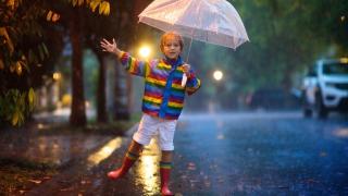 Lapsi sateenvarjon alla kadulla