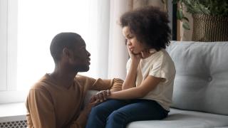 Vanhempi keskustelee lapsen kanssa sohvalla