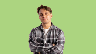 VAKEn harjoittelija poseeraa kameralle vihreää taustaa vasten.