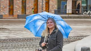 Henkilö istuu sateenvarjon alla