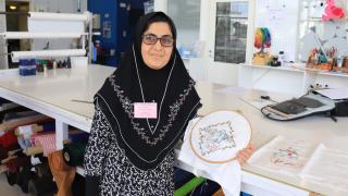 Henkilö esittelee kirjontatyötä