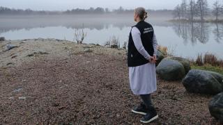 Henkilö järven rannalla "Sosiaali- ja kriisipäivystys" -liivissä