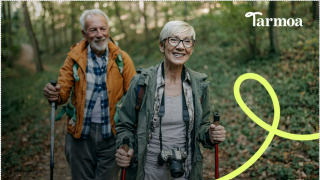 Tarmoa mainoskuva, nainen ja mies kävelevät metsässä. He molemmat hymyilevät.