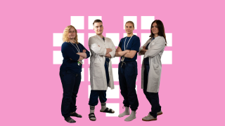 VAKEn työntekijät ryhmäkuvassa, seisovat pinkkiä taustaa vasten. 