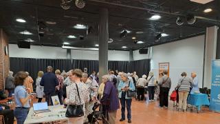 Kuvassa tapahtuma, jossa esittelypöytiä ja henkilöitä kiertämässä toimijoiden pisteitä.