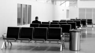 Mies yksin lentokentän terminaalissa