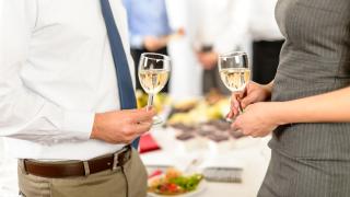 Kaksi henkilöä viinilasit kädessä.