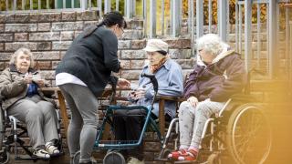 Ikääntyneitä ihmisiä istumassa tuolissa ja pyörätuoleissa.