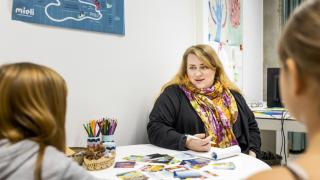 Kuvassa aikuinen nainen ja kaksi lasta pöydän ääressä.