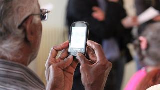 Iäkäs mies puhelin kädessä.